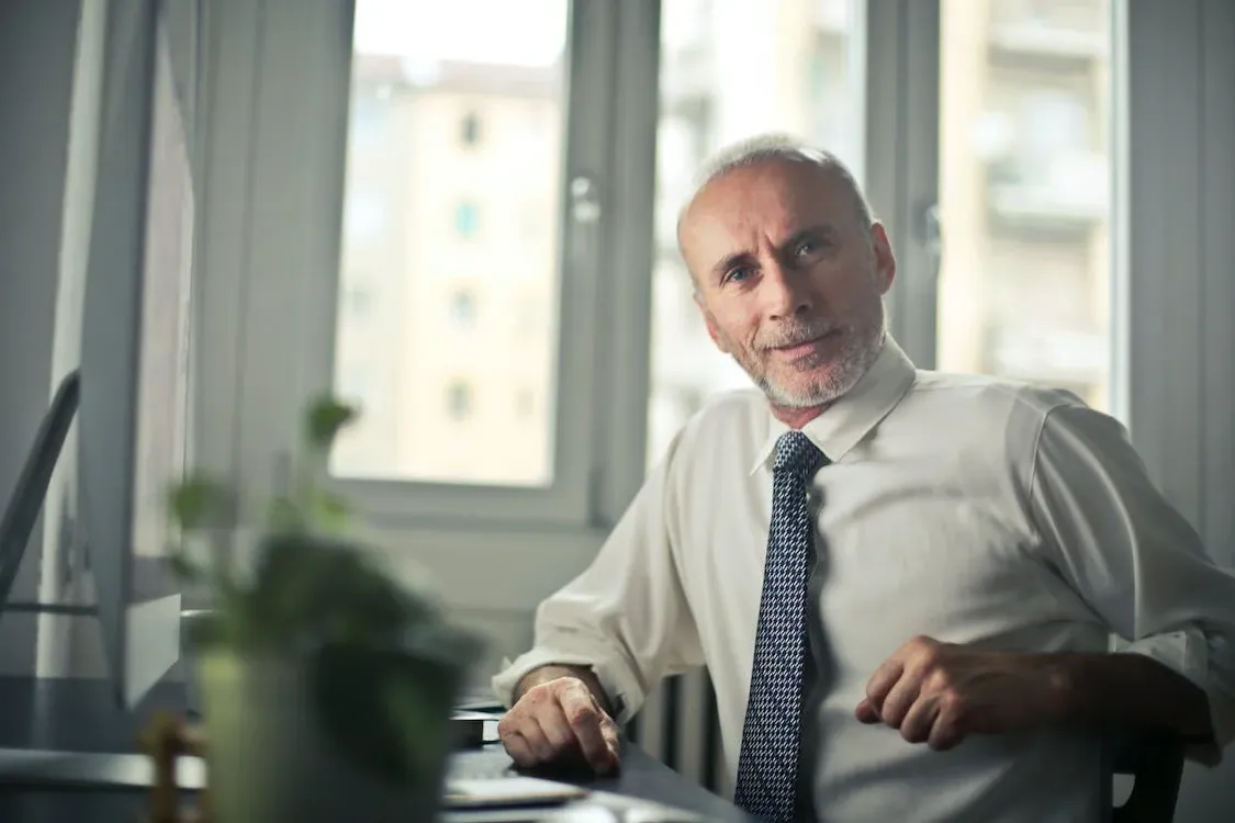 Personne âgée 50 ans et plus, homme en chemise et cravate assis à son bureau