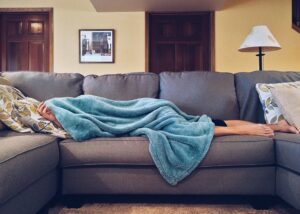 Personne allongée sur un divan sous une couverture, malade