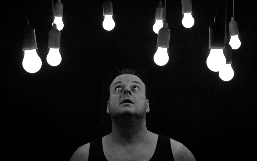 man looking up at illuminated light bulbs