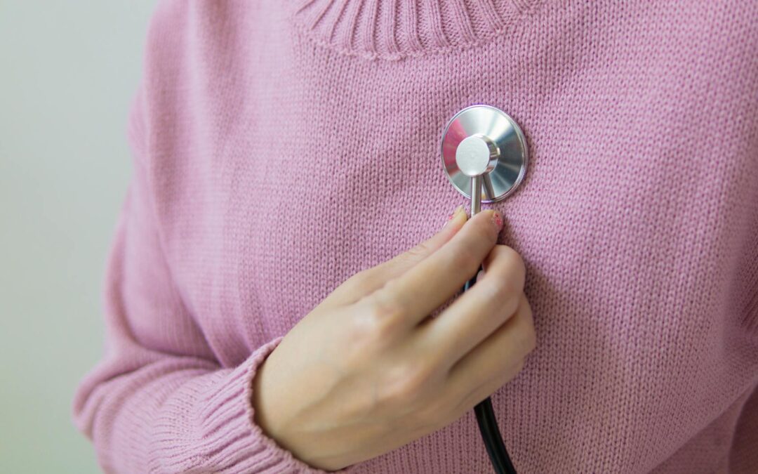 woman in pink sweater holding a stethoscope